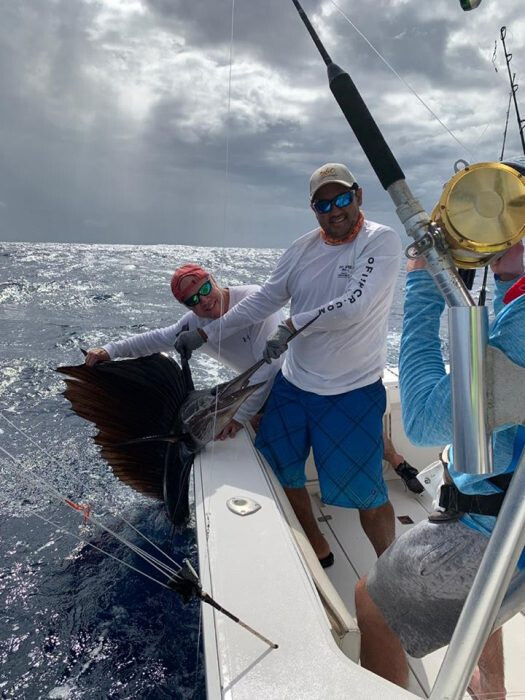 Fishing charter crew holding marlin