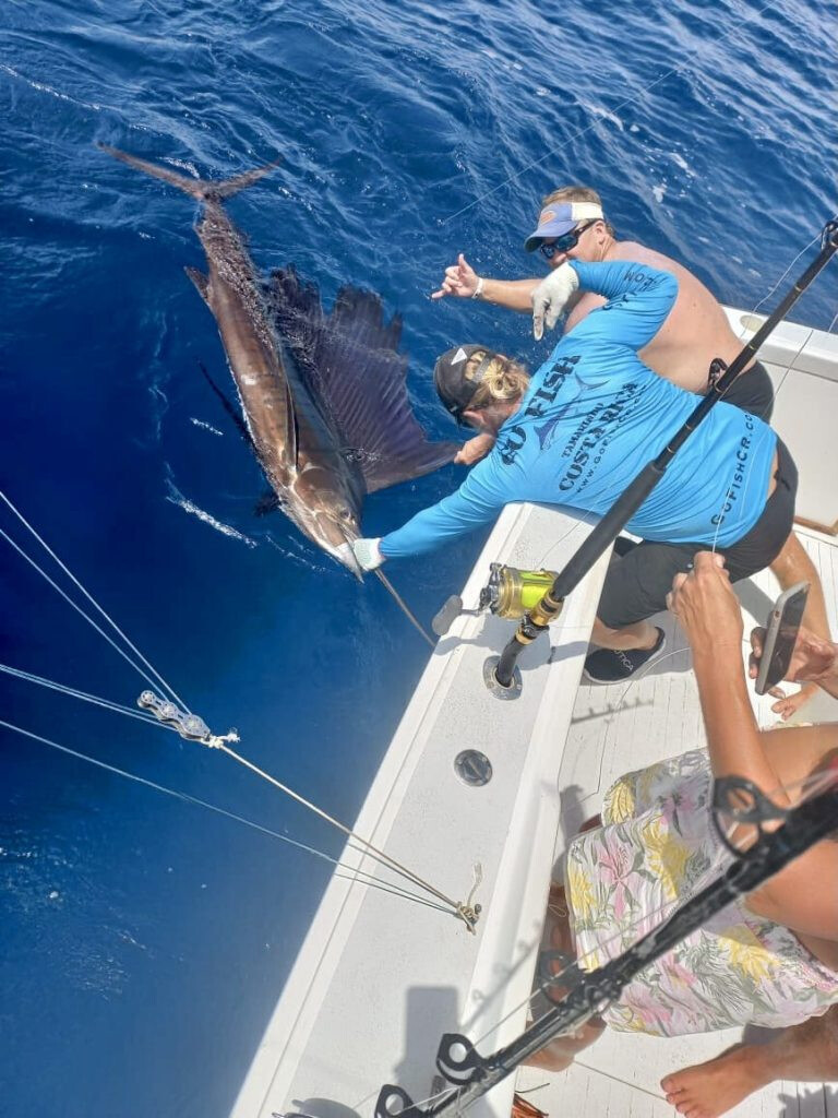 Crew member and man catching Marlin from boat