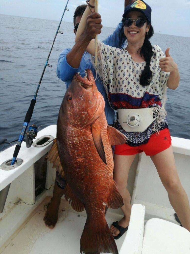 Woman holding red snapper she caught