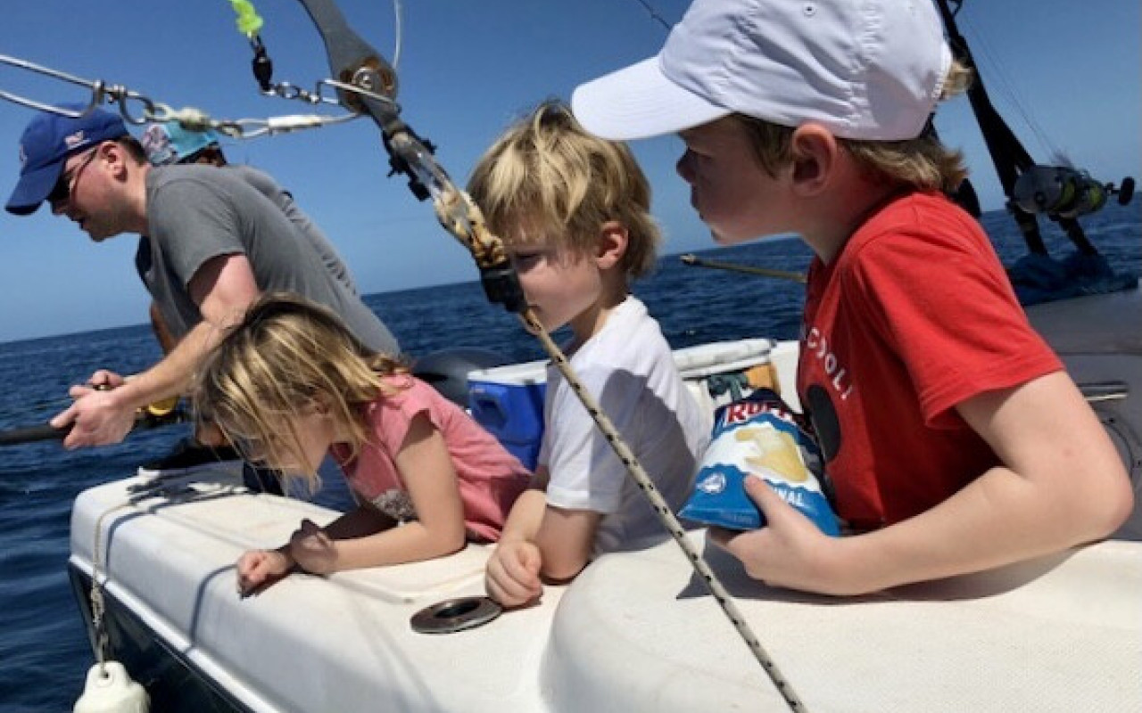 Father and children fishing from boat