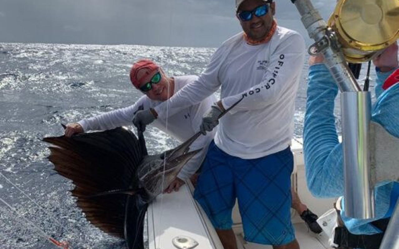 Fishing charter crew holding marlin