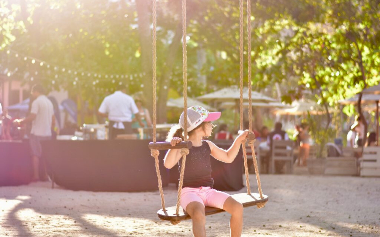 Girl sitting on wooden swing on beach