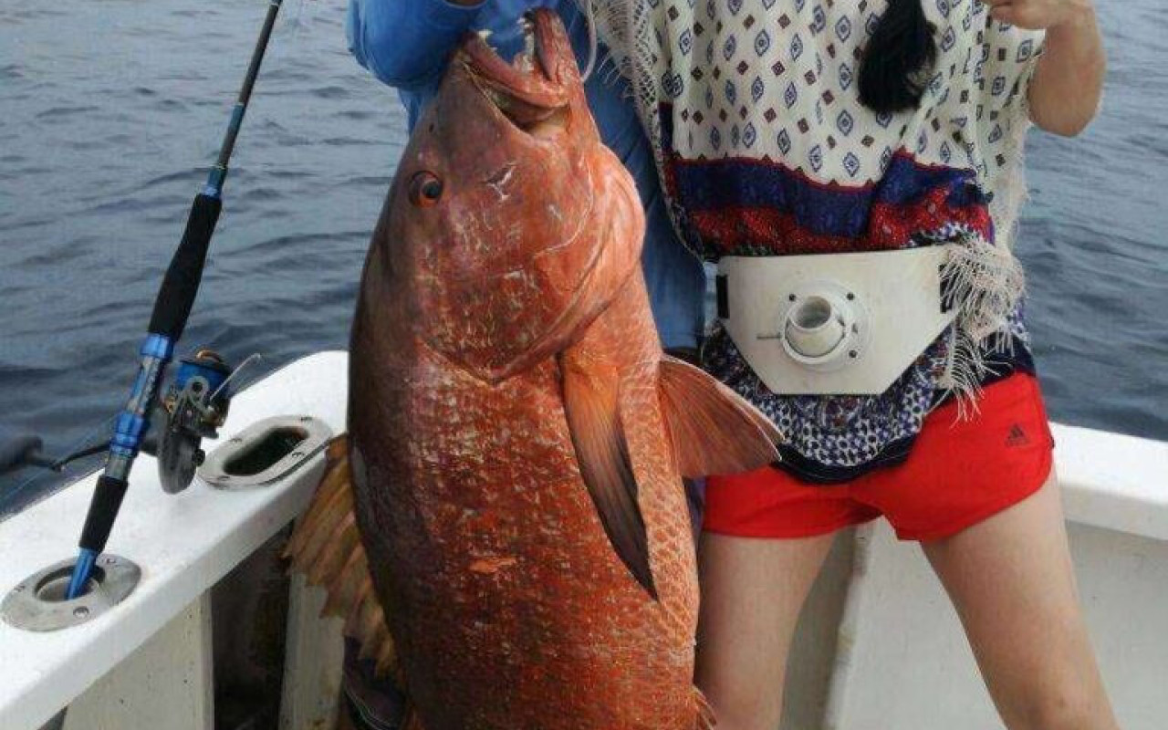 Woman holding red snapper she caught